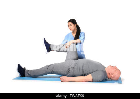 Young Asian physiotherapist working with senior man on white background Stock Photo