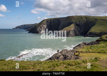 Rugged coastline at Ceibwr Bay near Cardigan in the Pembrokeshire coast national park. Tourists admiring the view on the rocks below. Stock Photo