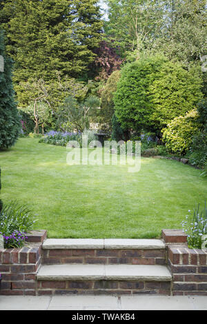 Terraced back garden with lawn, steps and patio in England, UK Stock Photo