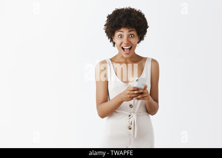 Woman excited and happy to reach lots of likes under her article in internet. Amazed grateful and pleased charming young African American female Stock Photo