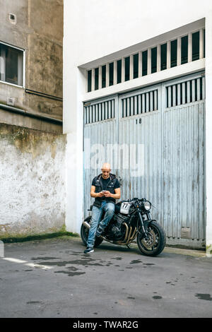 Biker looking mobile sitting on motorcycle Stock Photo