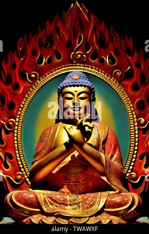 Statue of Buddha sitting in meditation with rich colours and detail in close up view Stock Photo