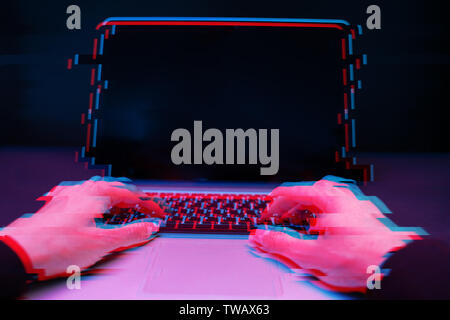 Hacker in the hood working with laptop typing text in dark room. Image with glitch effect Stock Photo