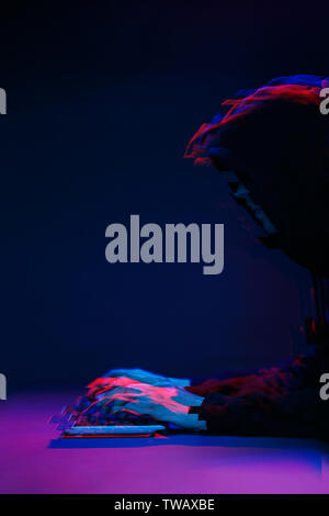 Hacker in the hood working with computer typing text in dark room. Image with glitch effect Stock Photo