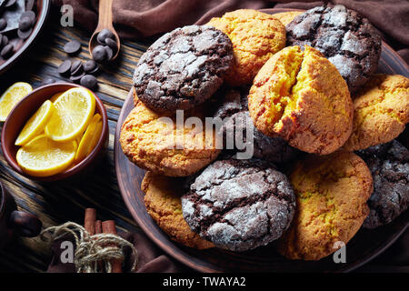 Crinkle cookies. Cracked lemon and chocolate biscuits on an earthenware plate on a rustic wooden table with ingredients, close-up Stock Photo
