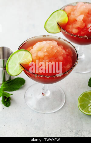 Red Frozen Margarita, refreshing cocktail on the table and lime with mint Stock Photo