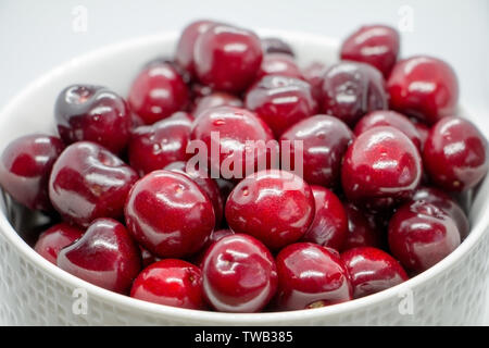 Ceramic white dish with washed fresh sweet cherries and water droplets. Bright, juicy, ripe berry in plate close up. Healthy juicy dessert background. Stock Photo