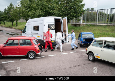 Mini plant, Oxford, UK. 19th June, 2019. Tribute to the Italian Job with a driving display and recreation of blowing the doors off the van to celebrate 60 years of Mini and 50 years since the release of the Italian Job film. The event was attended by Michael Deeley the  Oscar winning producer of the original film and David Salamone, a stunt driver who played Dominic in the original film in the red mini. Paul Swift (in white) led the driving stunts. Andrew Walmsley/Alamy Live News Stock Photo