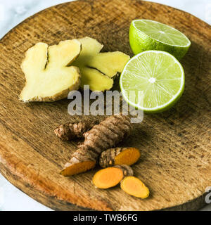 turmeric and ginger roots on a cutting board, cut with lime Stock Photo
