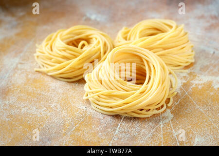 raw homemade spaghetti nest with flour on a wooden table. fresh Italian pasta Stock Photo