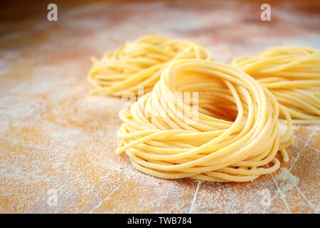 raw homemade spaghetti nest with flour on a wooden table. fresh Italian pasta Stock Photo