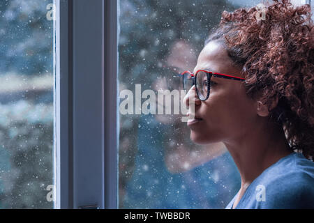 Lonely black woman near window thinking about something and winter snow