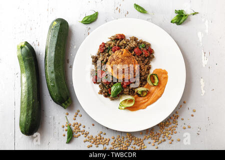 Boiled lentils with carrot puree and grilled zucchini. Colorful vegetable meatless dish. Stock Photo
