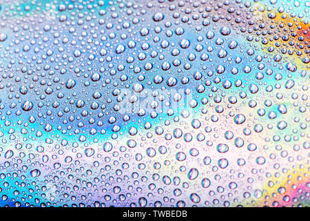 Drops of water on pastel holographic neon background. Macro shot Stock Photo