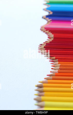 Rainbow of Pencils. A wave of coloured pencils in a row on a white background Stock Photo