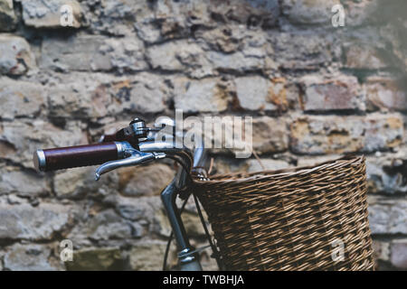 Vintage bicycle with leather handles and steel bell with wicker basket on the background of an old brick wall Stock Photo