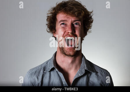 Screaming young man on gray background Stock Photo