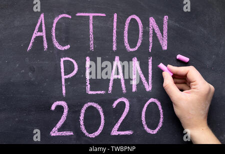 2020 goals concept. Woman hand writing action plan with chalk on black board, panorama, copy space Stock Photo