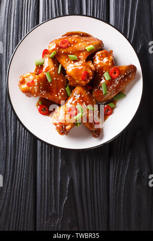 Asian chicken wings in teriyaki sauce close-up on a plate on the table. Vertical top view from above Stock Photo