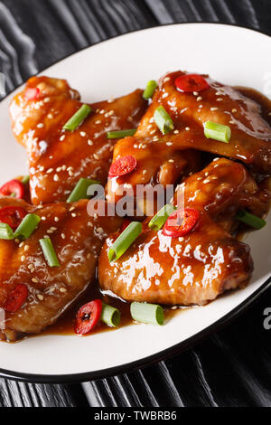 Asian chicken wings in teriyaki sauce close-up on a plate on the table. vertical Stock Photo