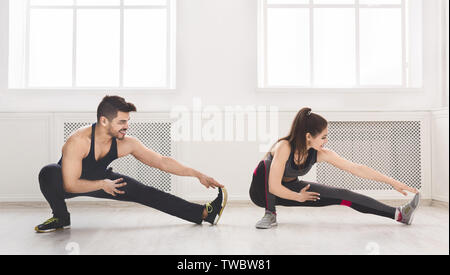 Sporty couple stretching legs before training in studio, panorama, copy space Stock Photo