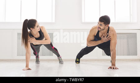 Young fit couple standing in plank with one hand and looking at each other, panorama, free space Stock Photo