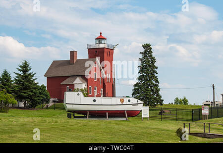 Two Harbors, Minnesota - July 3, 2010: Two Harbors Light Station, the oldest operating lighthouse in Minnesota, with Crusader II Lake Superior Fishing Stock Photo