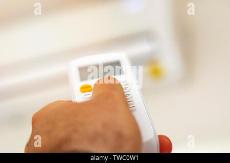 close-up view of a hand adjusting the air conditioning temperature using the remote control. Home comfort. Air conditioning and appliances Stock Photo