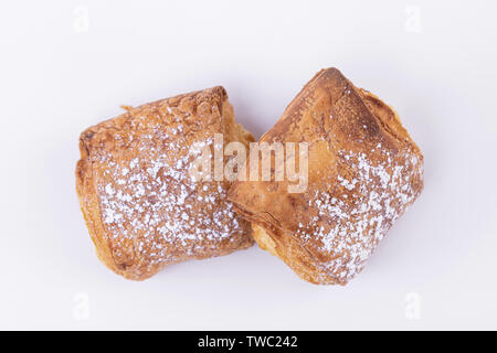 Top view of two freshly baked puff pastries with powdered sugar sprinkled on top on a white background Stock Photo