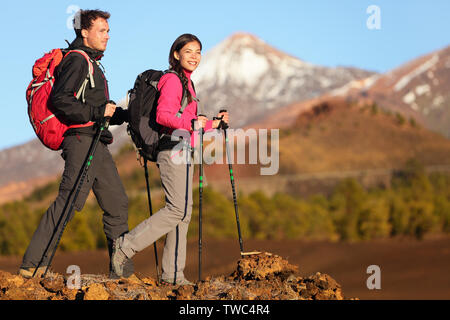 Hikers people hiking - healthy active lifestyle. Hiker people hiking in beautiful mountain nature landscape. Woman and man hikers walking during hike on volcano Teide, Tenerife, Canary Islands, Spain. Stock Photo