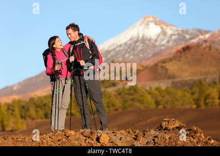 Healthy active lifestyle. Hiker people hiking in beautiful mountain nature landscape. Woman and man hikers laughing resting taking break during hike on volcano Teide, Tenerife, Canary Islands, Spain. Stock Photo