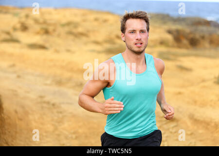 Man running outdoors in nature. Fit male runner jogging outside training cross country trail running. Handsome male sports fitness model in his 20s. Stock Photo