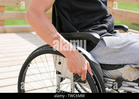 Disabled young athletic man on a wheelchair holding and turning wheels with hand engage in sports Stock Photo