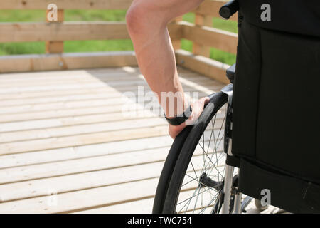 Disabled young man on a wheelchair holding and turning wheels with hand Stock Photo