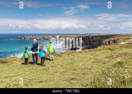 A mother and her three children looking out over the rugged, spectacular coastline at Carnewas and Bedruthan Steps on the North Cornwall Coast.  Mothe Stock Photo