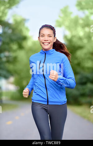 Happy woman runner healthy lifestyle concept with girl jogging smiling training outside in park for marathon. Beautiful mixed race Asian Caucasian female model fresh and vivacious. Stock Photo