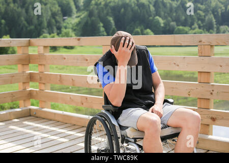 Disabled young man on a wheelchair in nature feeling depressed, lonely and sad Stock Photo