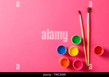 Flat lay composition with gouache and paint brushes on pink background, space for text Stock Photo