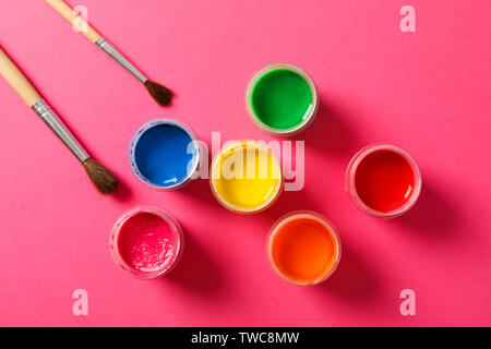 Flat lay composition with gouache and paint brushes on pink background, space for text Stock Photo