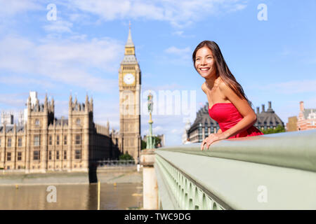 London - happy woman by Big Ben in England. Beautiful tourist girl sightseeing travel on Westminster Bridge, London, England, United Kingdom. Multiracial Asian Caucasian female model travelling. Stock Photo