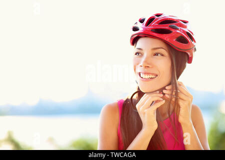 Bike helmet - woman putting biking helmet on outside during bicycle ride. Stock Photo