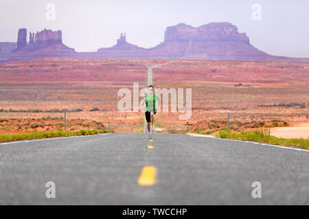 Running man - runner sprinting on road by Monument Valley. Concept with sprinting fast training for success. Fit sports fitness model working out in amazing landscape nature. Arizona, Utah, USA.