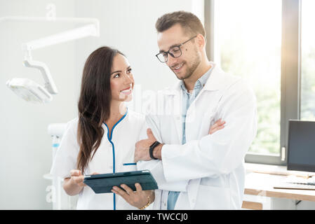 Medical workers working together in office. Female doctor holding digital tablet. Stock Photo