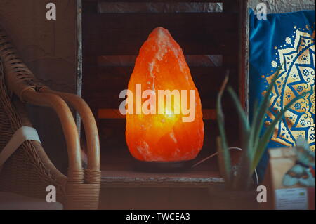 Himalayan salt lamp on wooden table illuminated Stock Photo