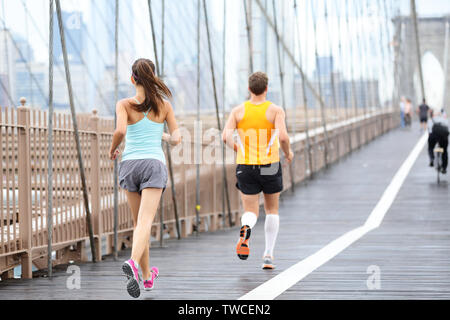Running people jogging training for New York marathon. Runners on run outside. Man runner and woman fitness sport model jogging on Brooklyn Bridge, New York City, USA. Stock Photo