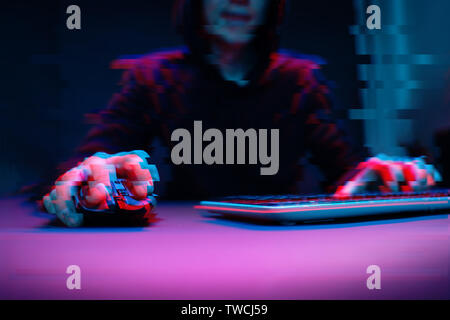 Hacker in the hood working with computer typing text in dark room. Image with glitch effect Stock Photo