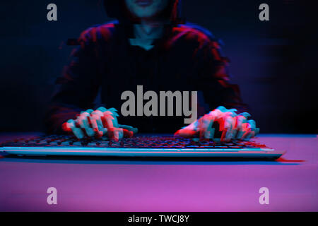 Hacker in the hood working with computer typing text in dark room. Image with glitch effect Stock Photo