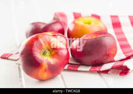 Ripe flat nectarines on white table. Stock Photo