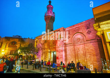 CAIRO, EGYPT - DECEMBER 22, 2017: The crowded Al-Muizz street in front of ornate medieval Al Aqmar Mosque in dimmed evening lights, on December 22 in Stock Photo