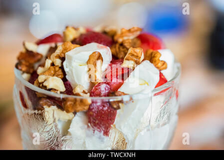 Vanilla ice cream with strawberry and walnut in bowl on blurred background Stock Photo